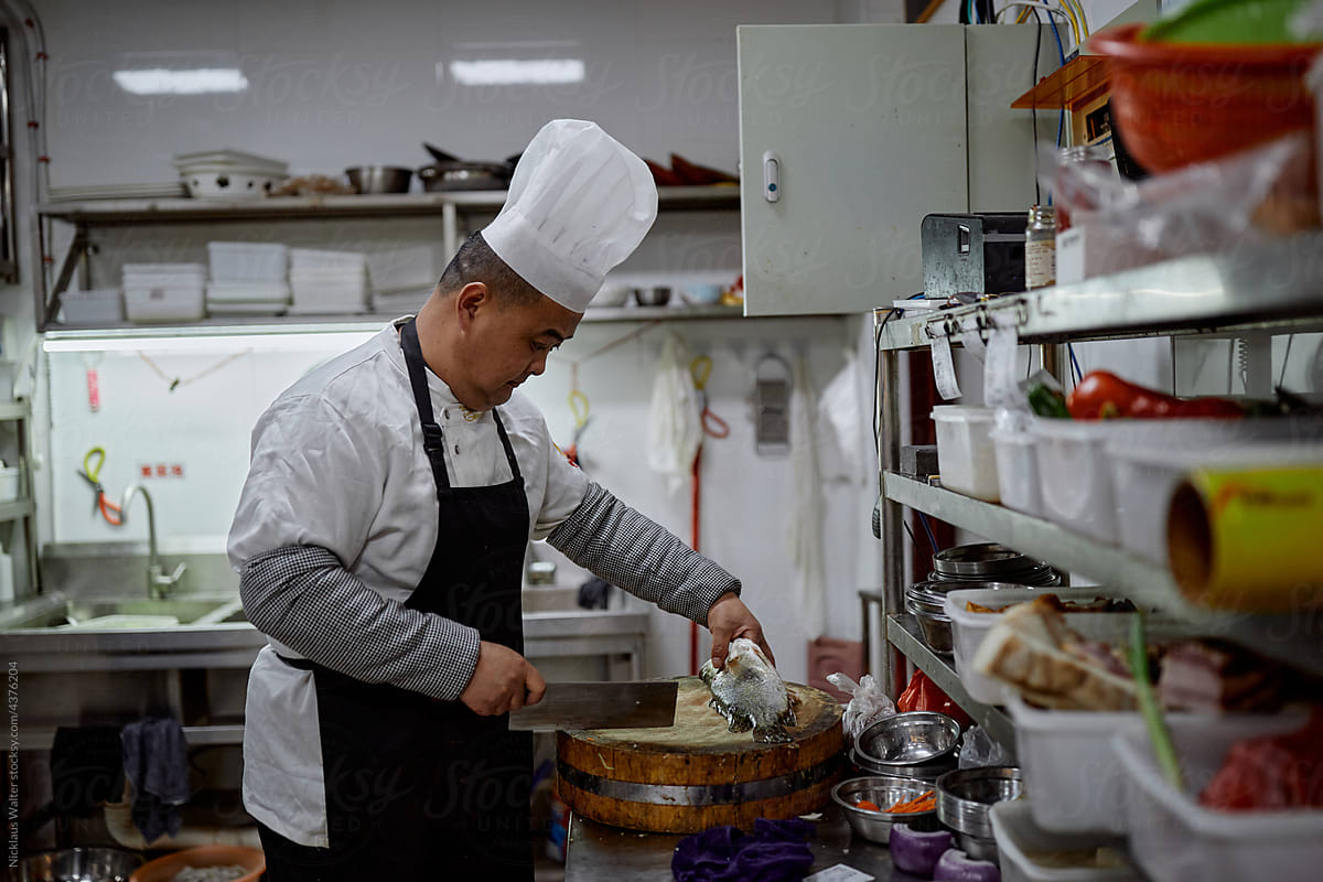 Chinese chef prepares fish in a restaurant kitchen