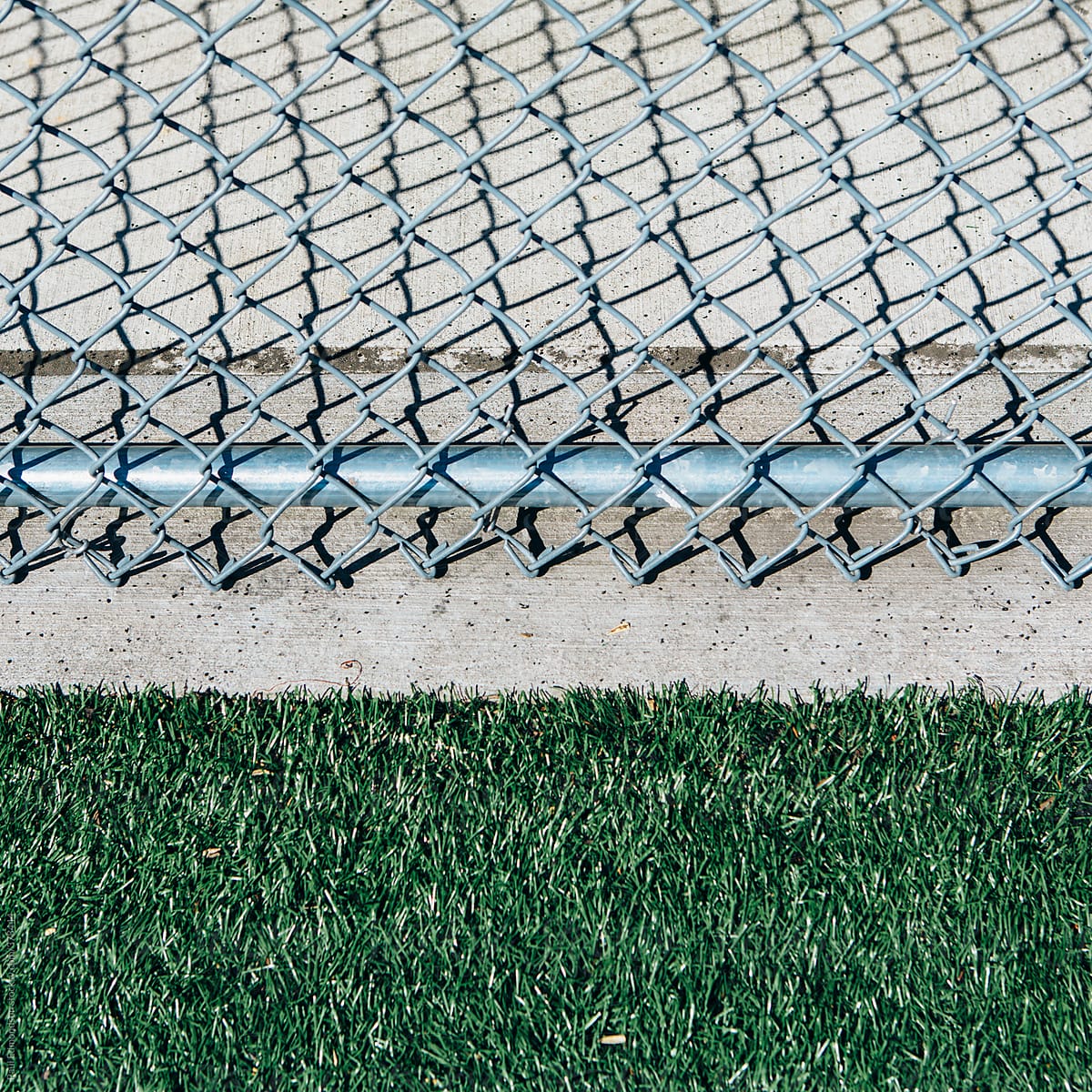 Chain link fence on edge of artificial turf sports field, close up