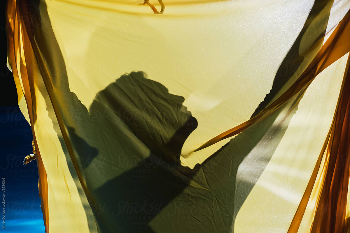 A man's silhouette behind a yellow sheet