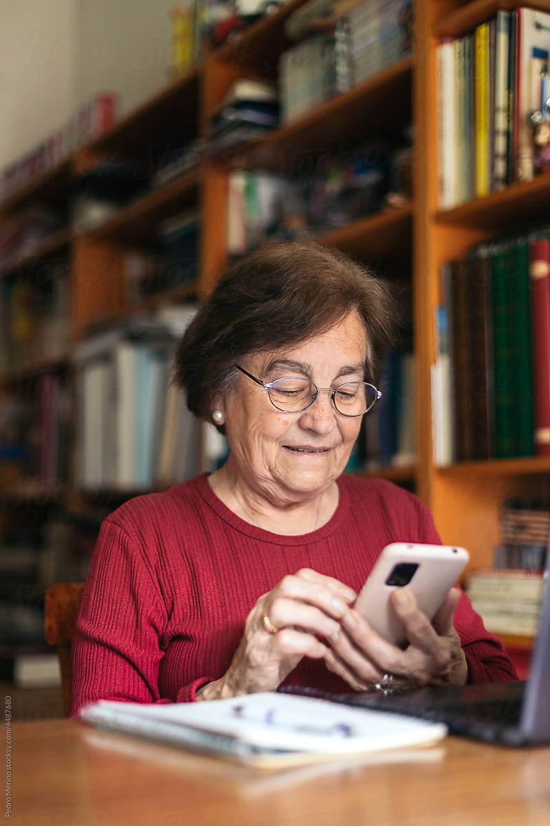 Elderly woman using computer and mobile phone