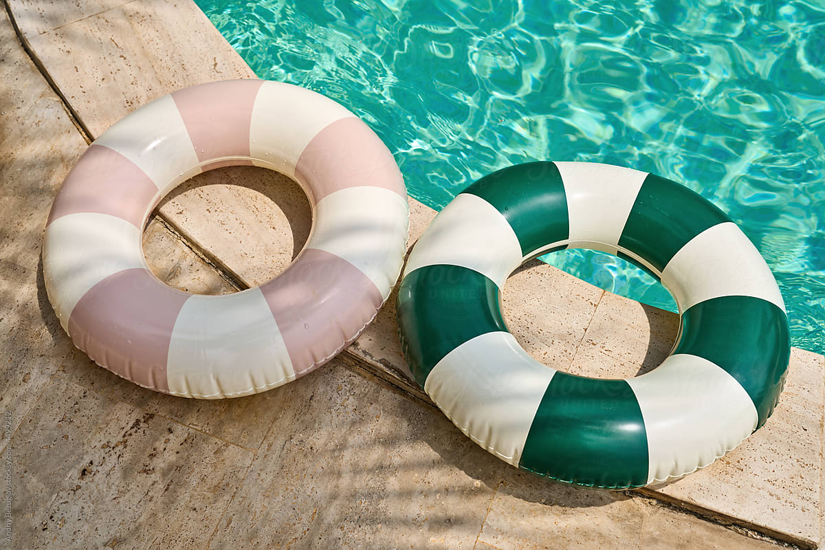 Multicolored swimming tubes on beige tiled poolside