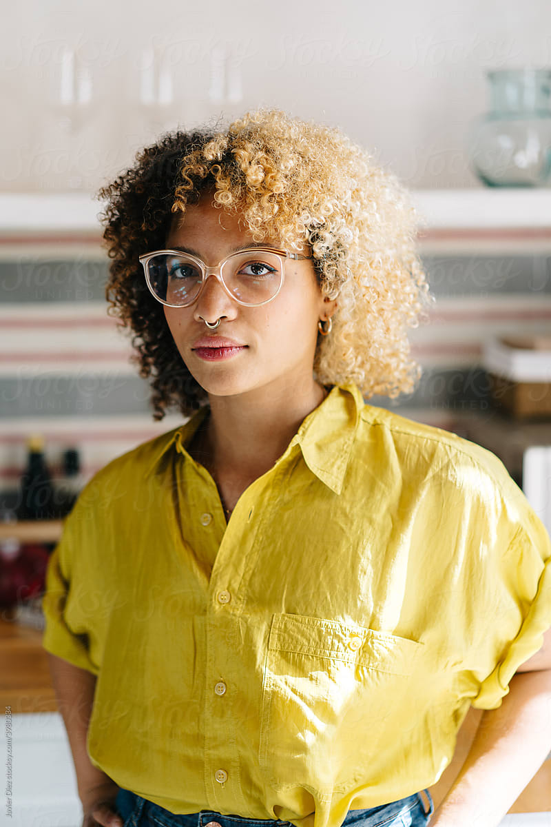Young curly haired woman in eyeglasses looking at camera