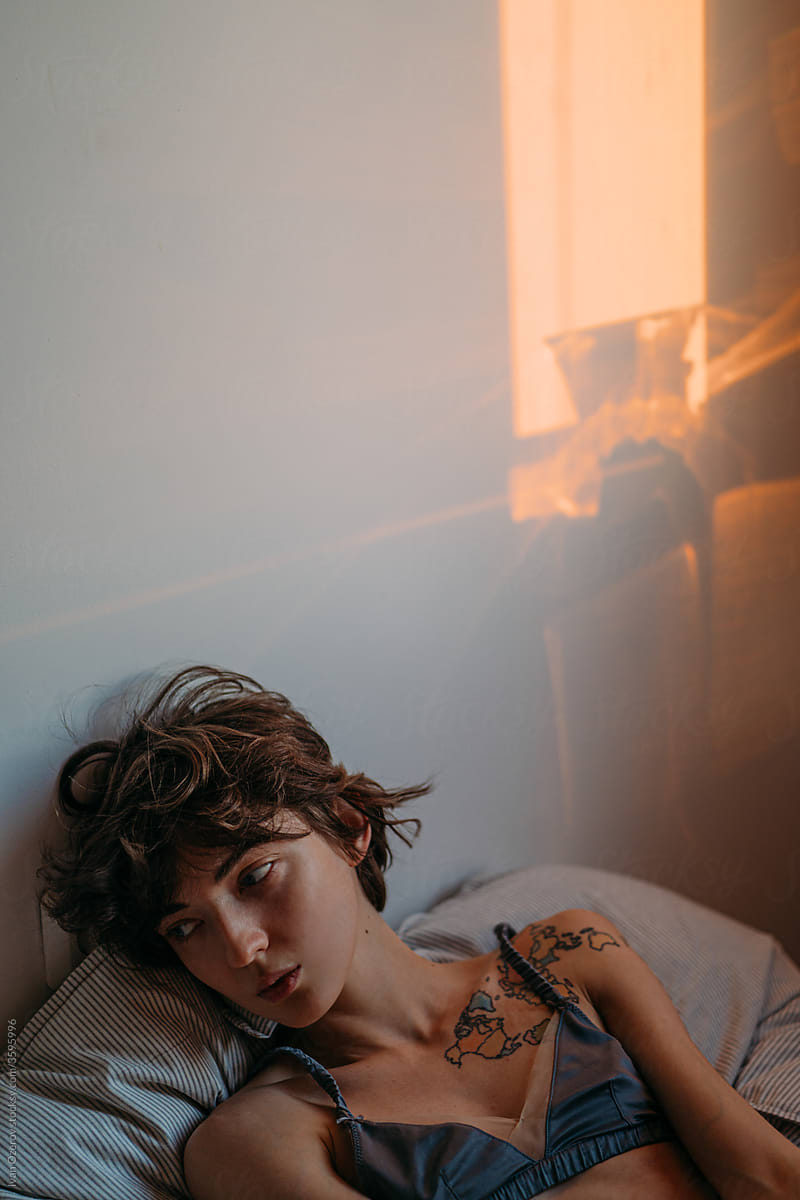 a young woman lies on a bed during dawn