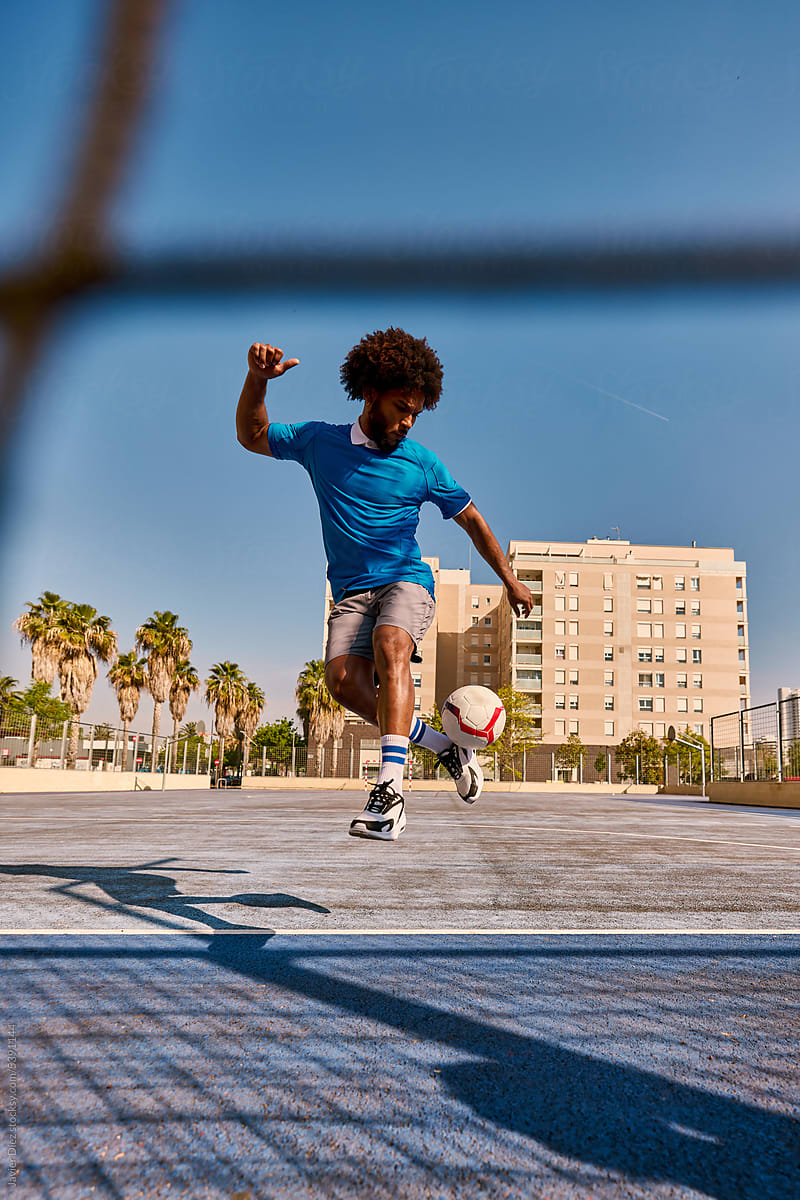 Energetic black football player kicking ball