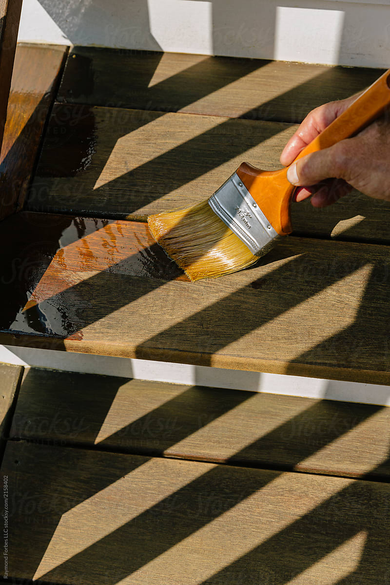 Close up of Hand work Applying Stain on Wood on porch deck of home