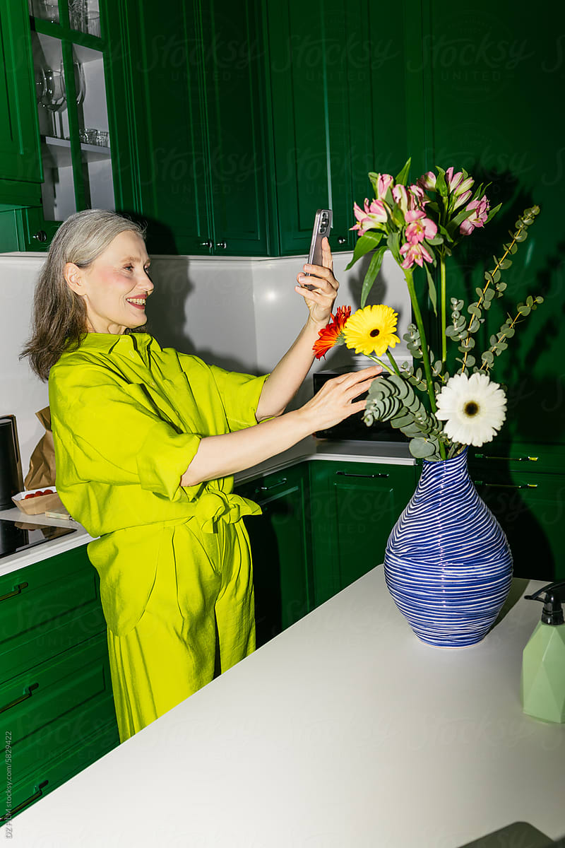 A woman photographs a bouquet at home