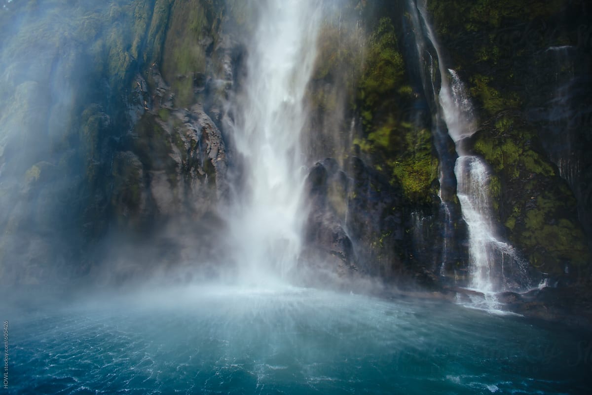 A large waterfall pours into the basin of Milford Sound, New Zealand