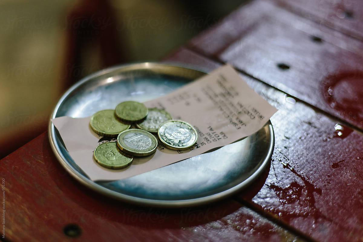 Euro money change and receipt on plate at restaurant bar table