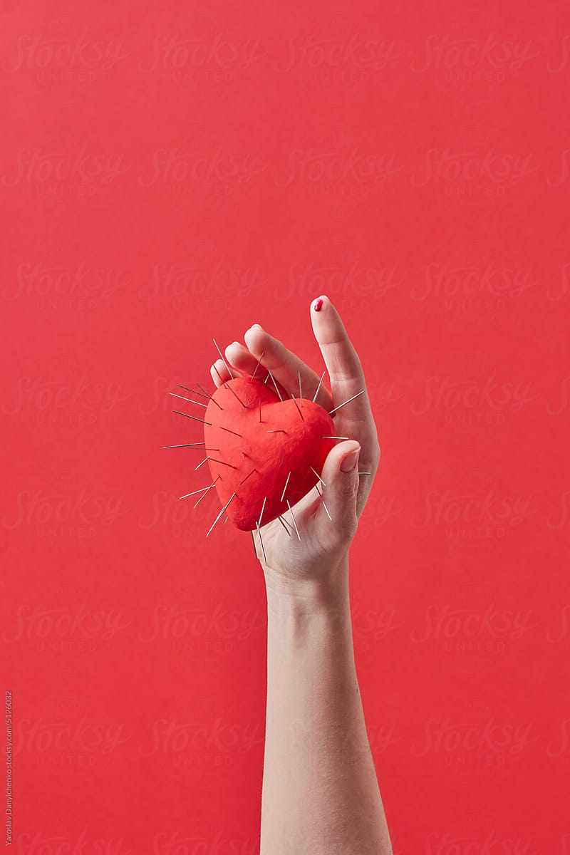 Red heart with thorns in woman\'s hand.
