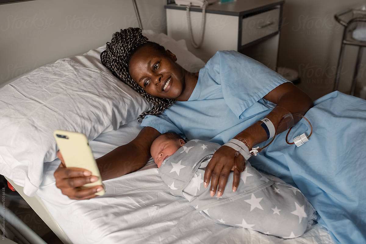 African mother with baby making video call in hospital