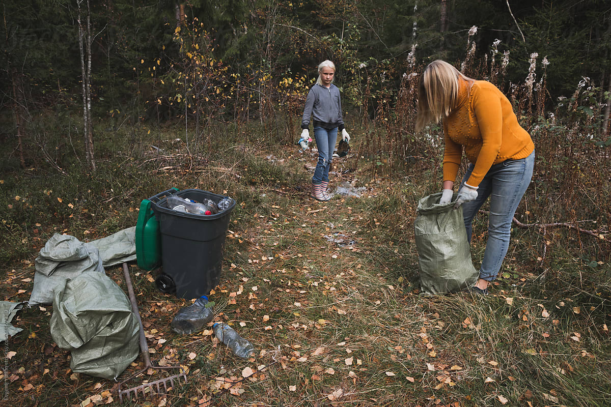 Woman and her daughter collect plastic litter in the forest