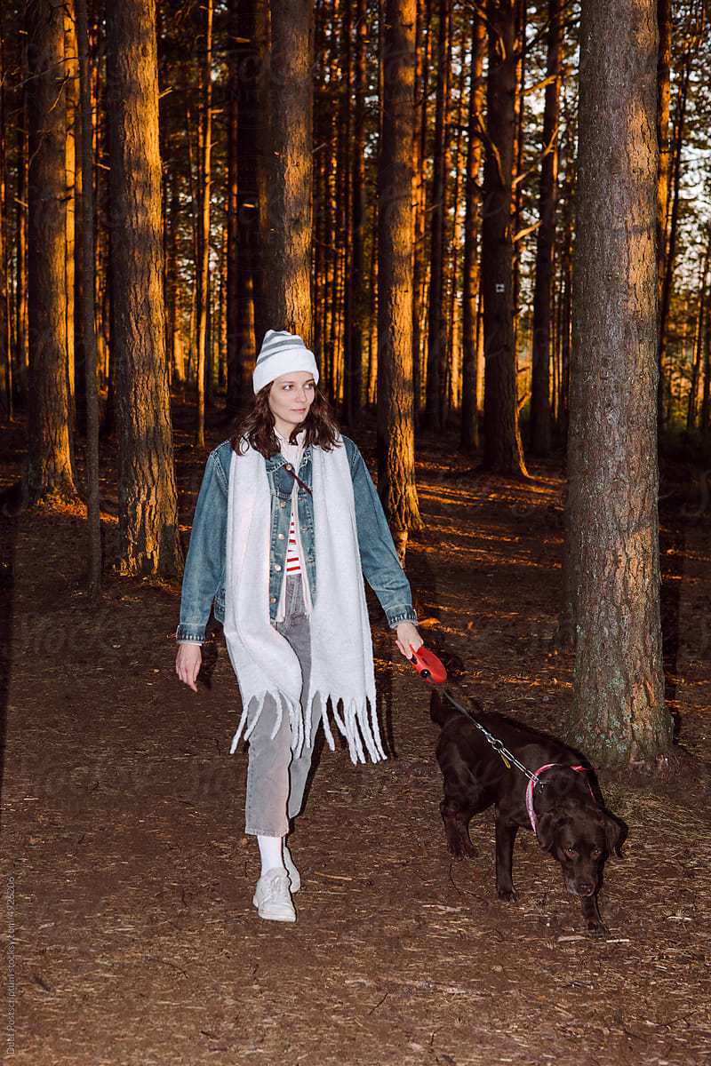 Young woman walks his dog in nature in the evening