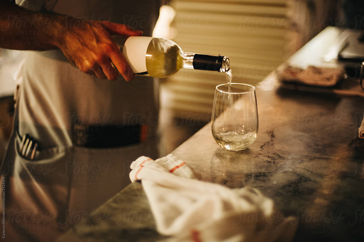 Anonymous server pouring a glass of white wine