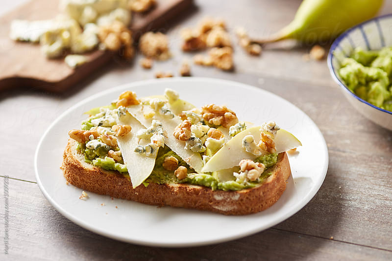 Close-up of fresh tasty avocado toast with blue cheese,nuts and pear
