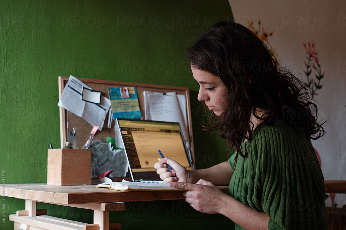 woman writing notes in diary at her desk