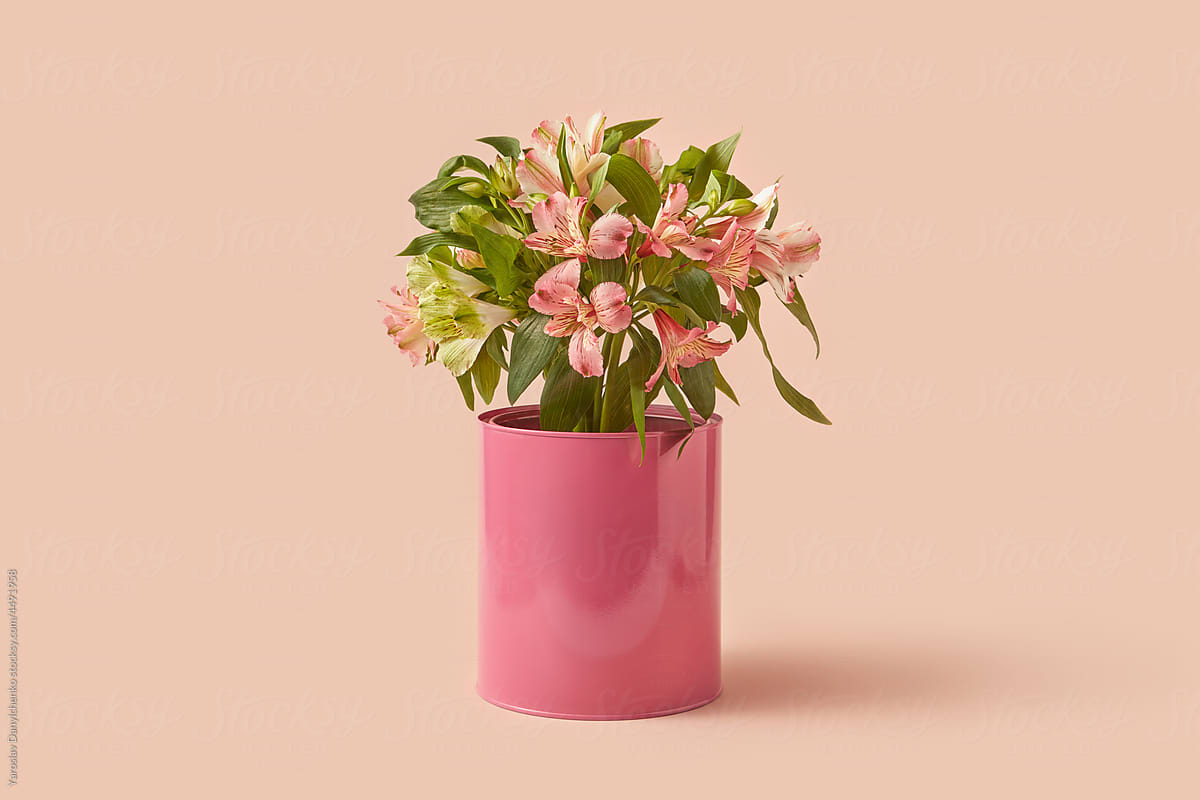 Tin can of pink paint with spring flowers inside