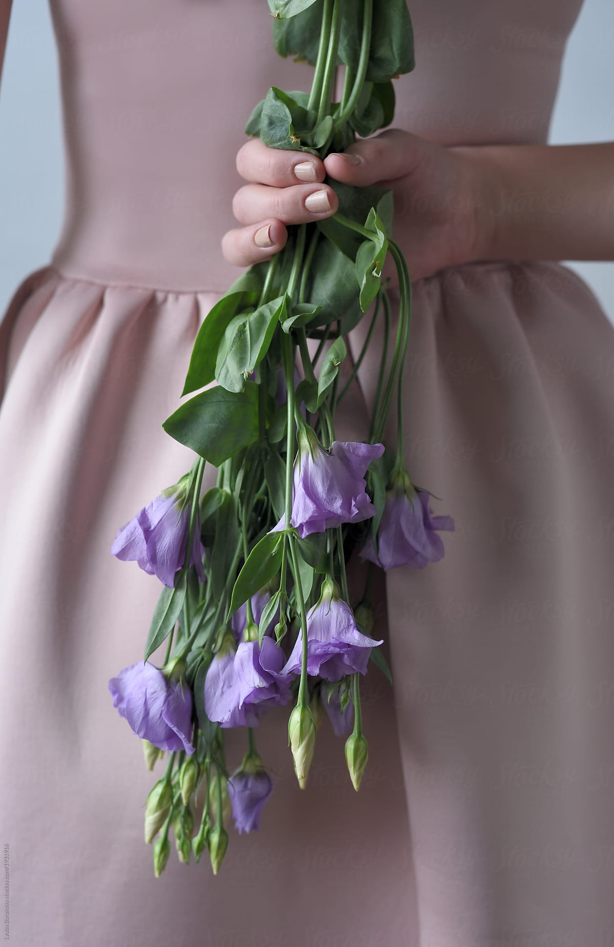 Girl holding violet eustoma flowers behind her back
