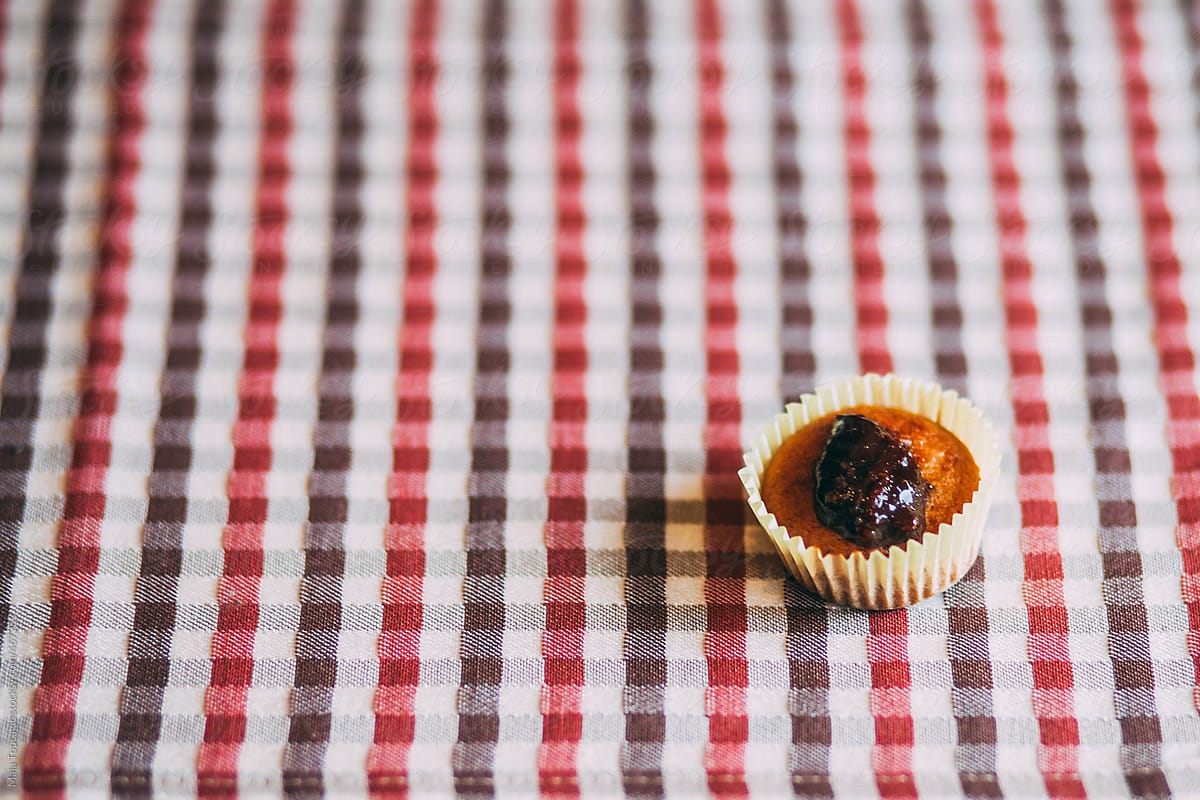 Fresh healthy homemade muffin with plum jam on a plaid table cloth
