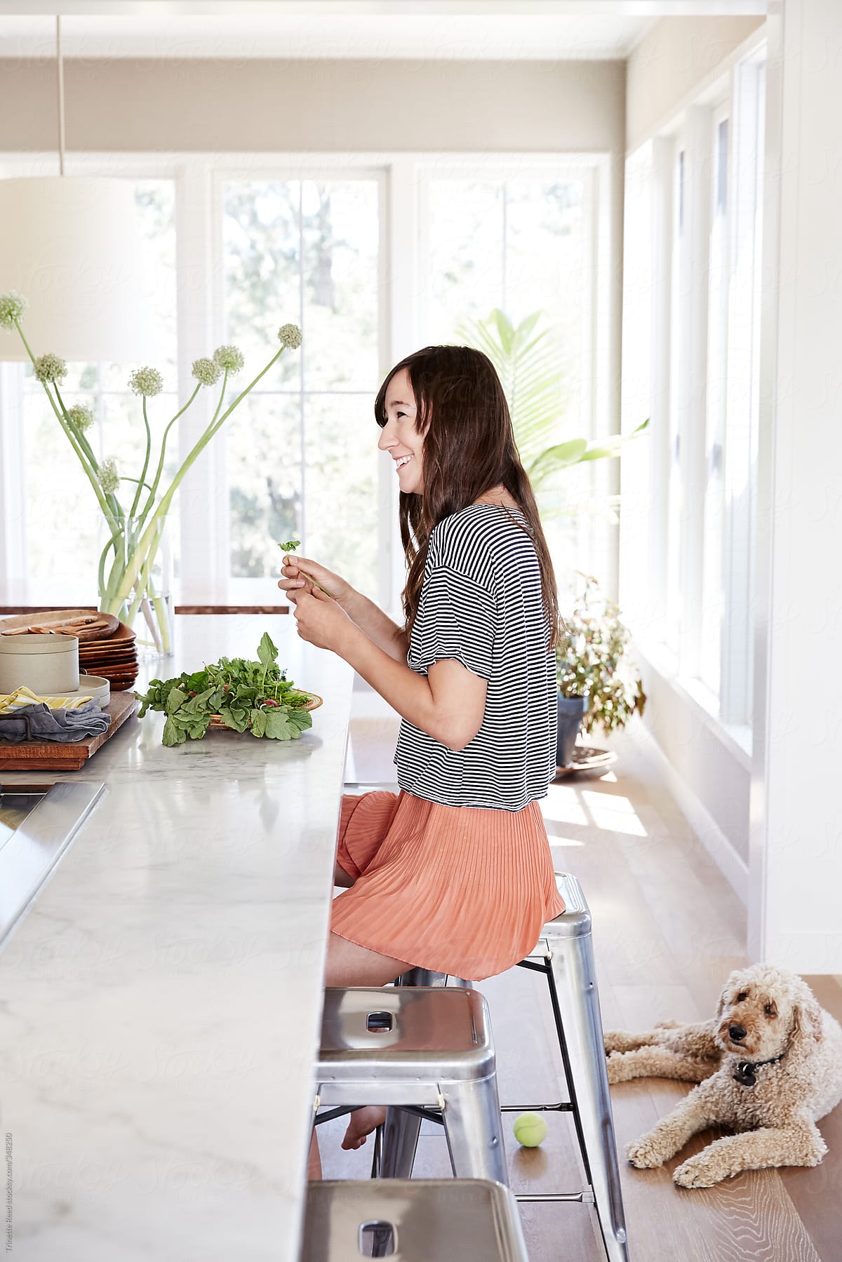 Woman with herbs at kitchen counter with pet dog