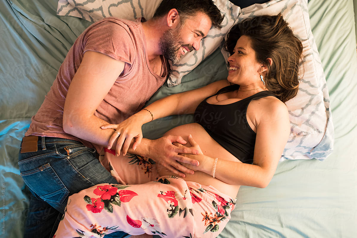Happy couple enjoying pregnancy on bed