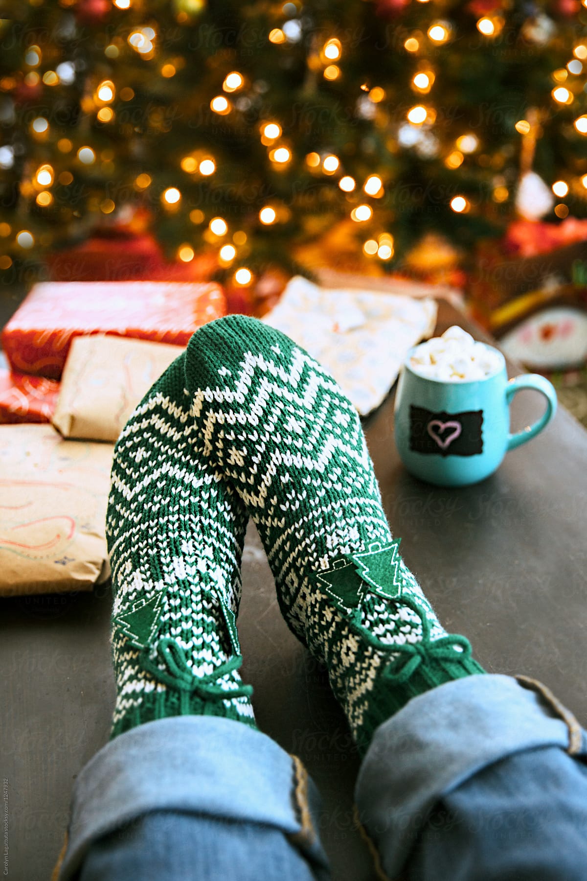 Feet with Christmas socks in front of the tree and wrapped presents