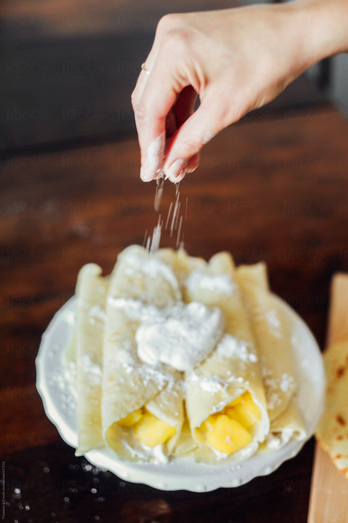 hand sprinkling coconut on crepes