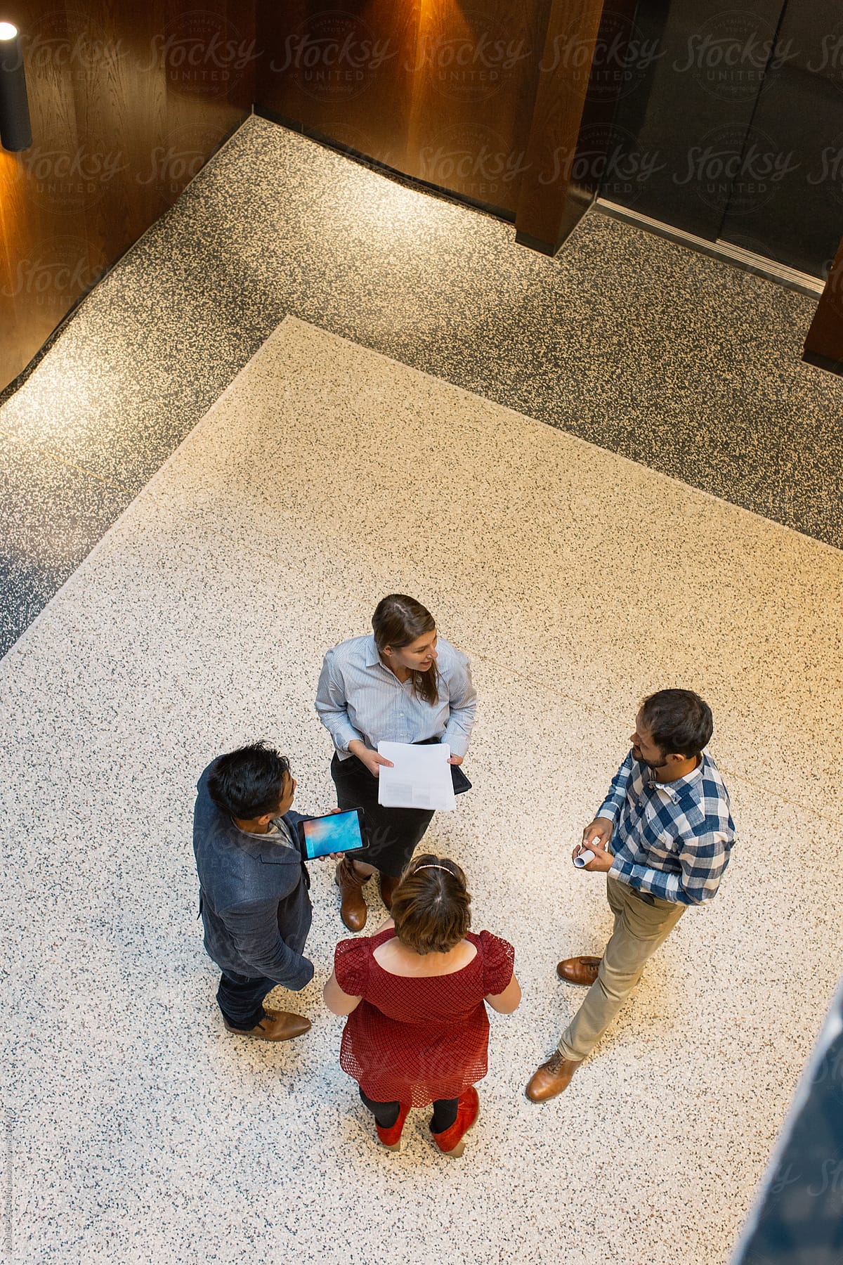 Overhead Shot of Four Businesspeople Discussing in Bright Hallway