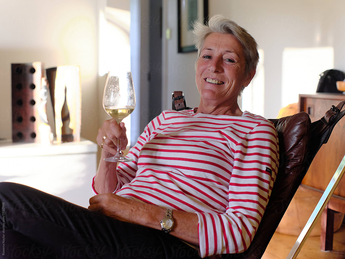Portrait of relaxed older lesbian at home enjoying a glass of wind