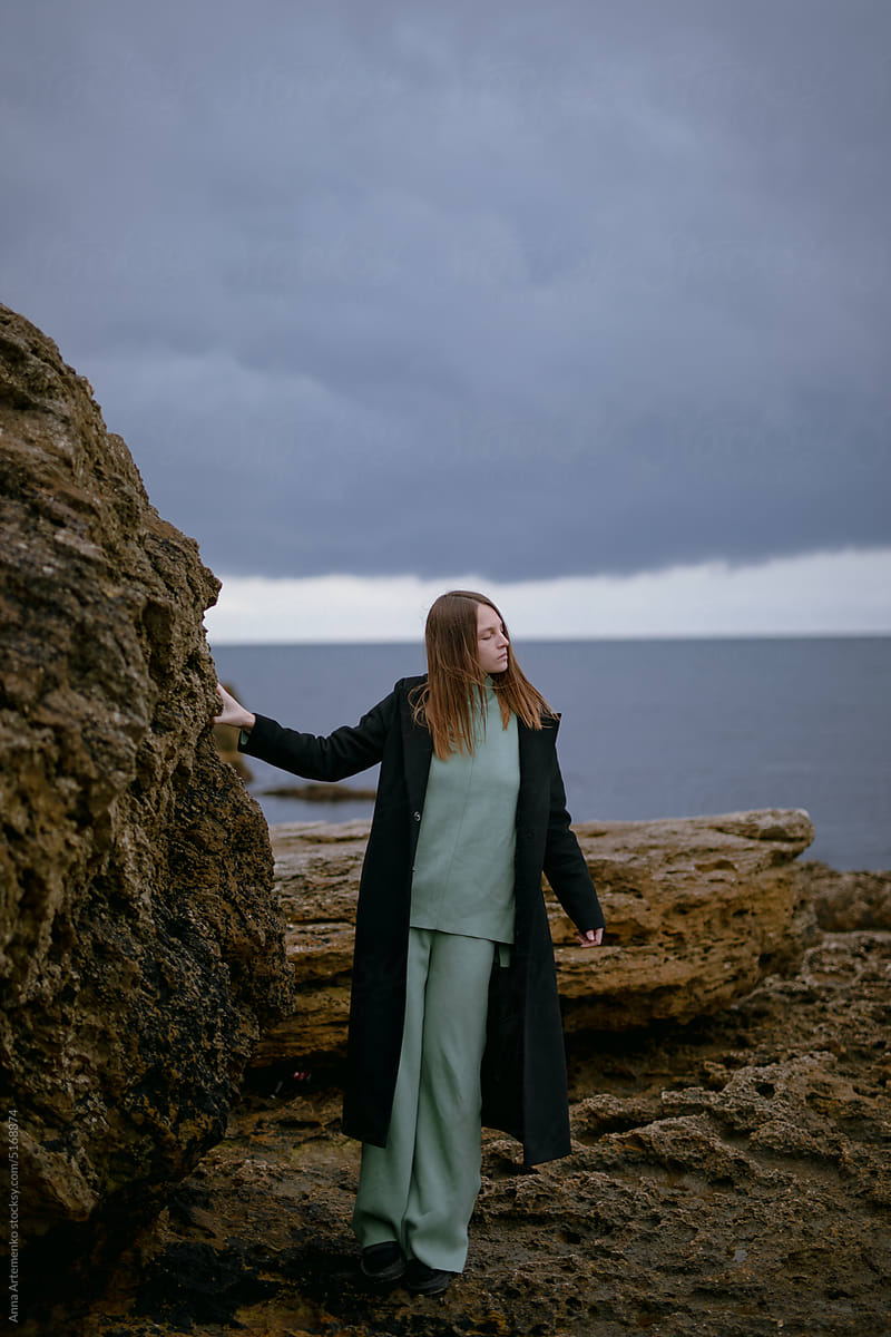 Portrait of a young girl in a black coat near the sea