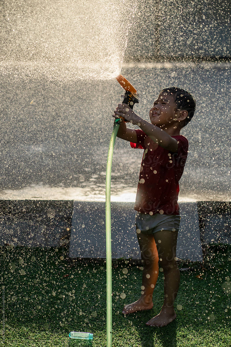 Boy Spraying water in golden sunlight