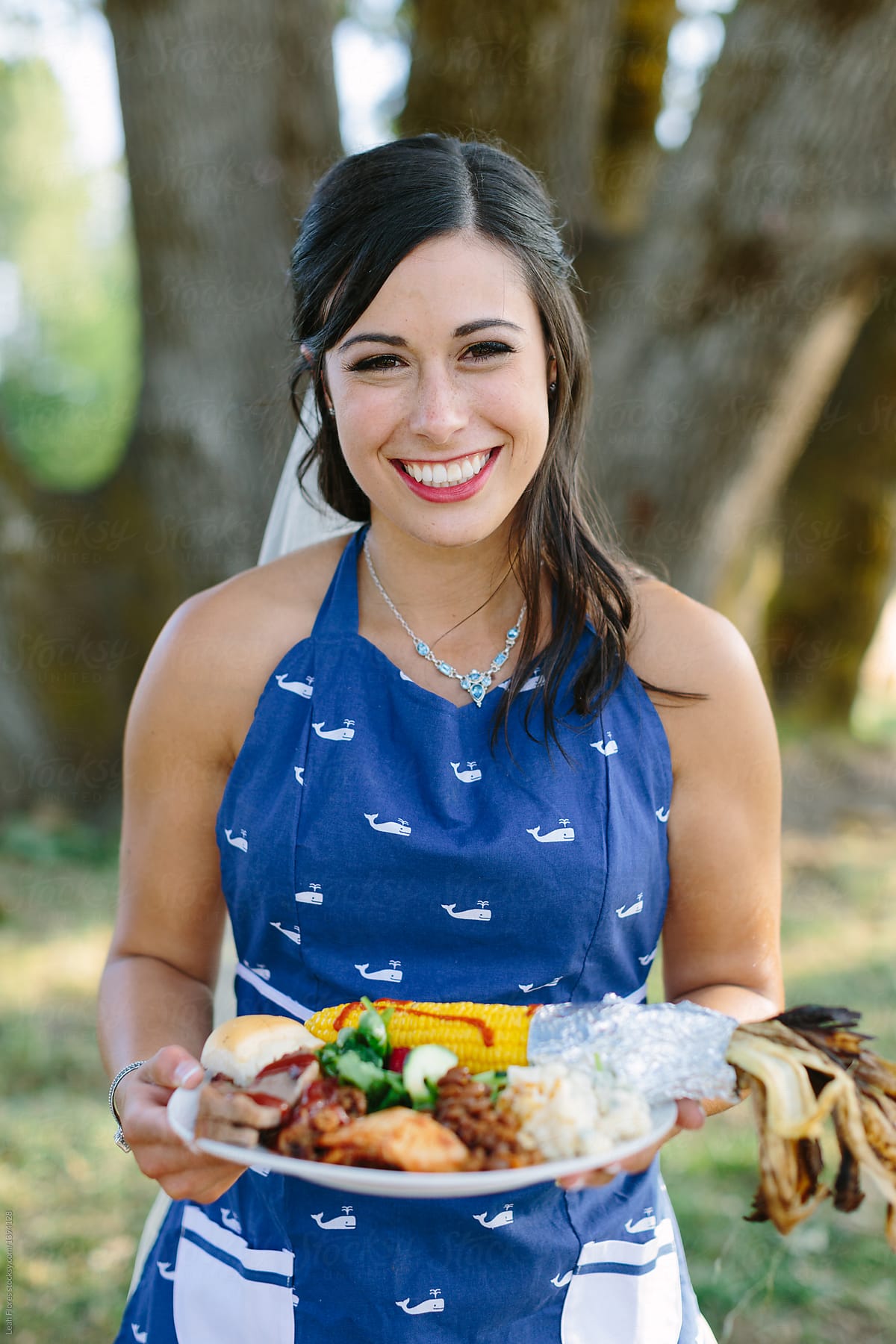 Woman Holding Plate Of Barbecue Food While Wearing Cute Whale Apron by Stocksy  Contributor Leah Flores - Stocksy