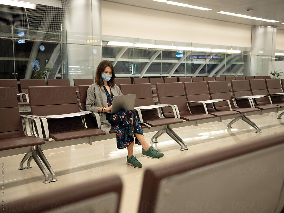 Woman in mask with laptop in empty airport