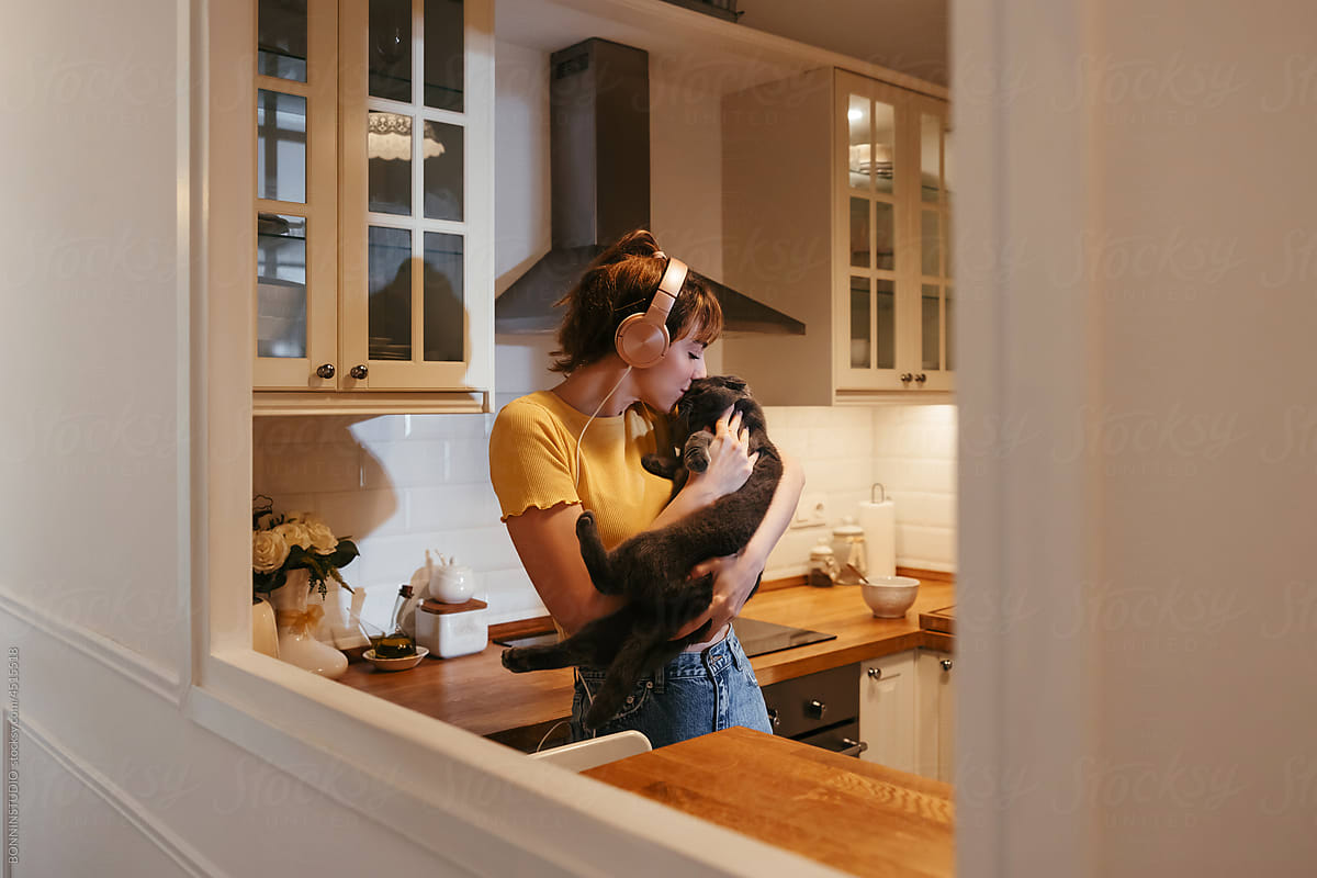 Gentle woman kissing and hugging cat at home
