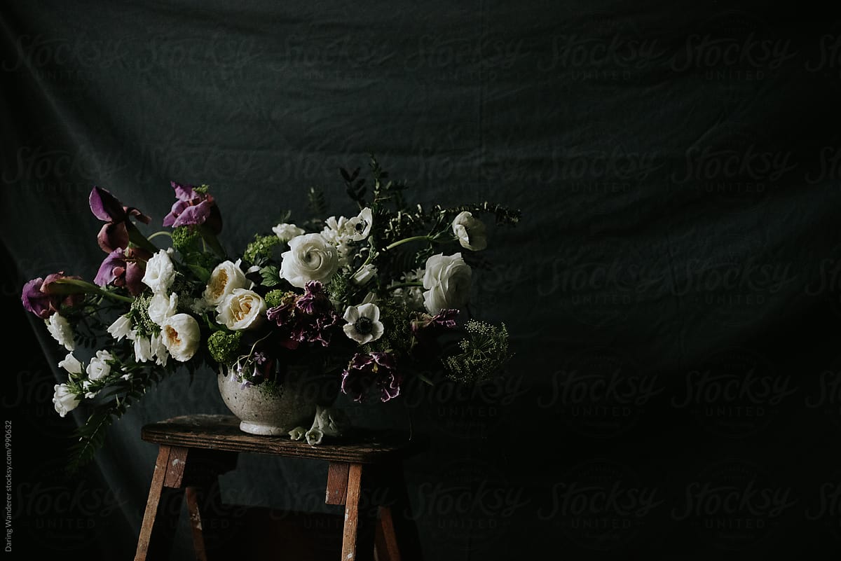 Dark and moody purple and white wedding flower arrangement with dark background