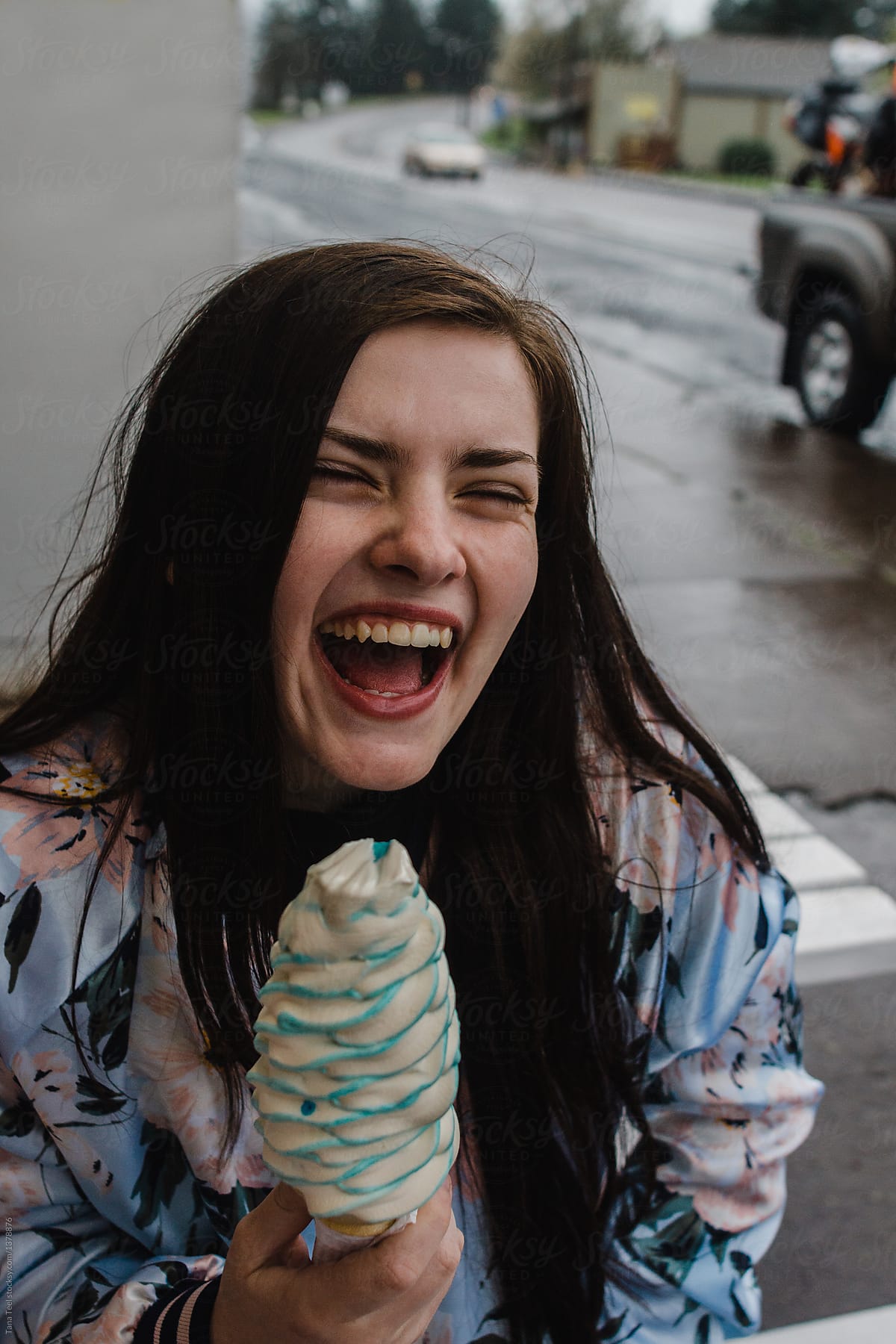 teenager enjoying ice cream cone on rainy day