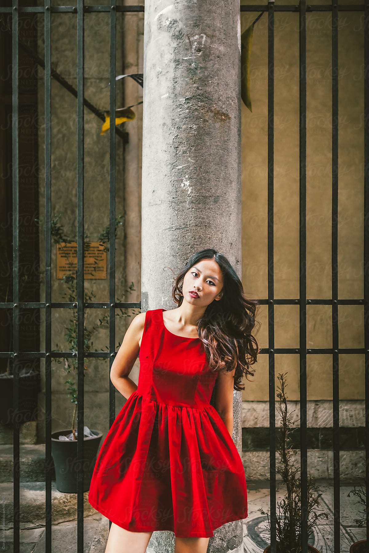 Red Dressed Young Asian Woman against an Old Column