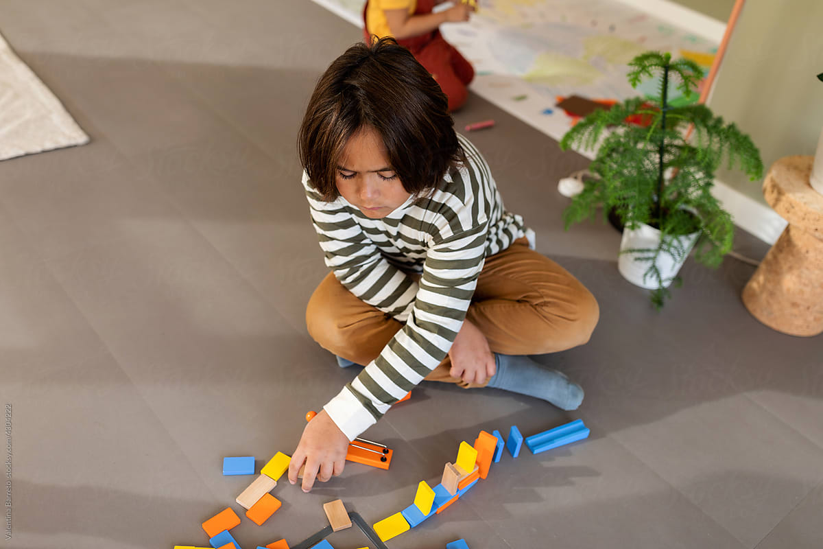 Boy playing with dominoes at playroom floor