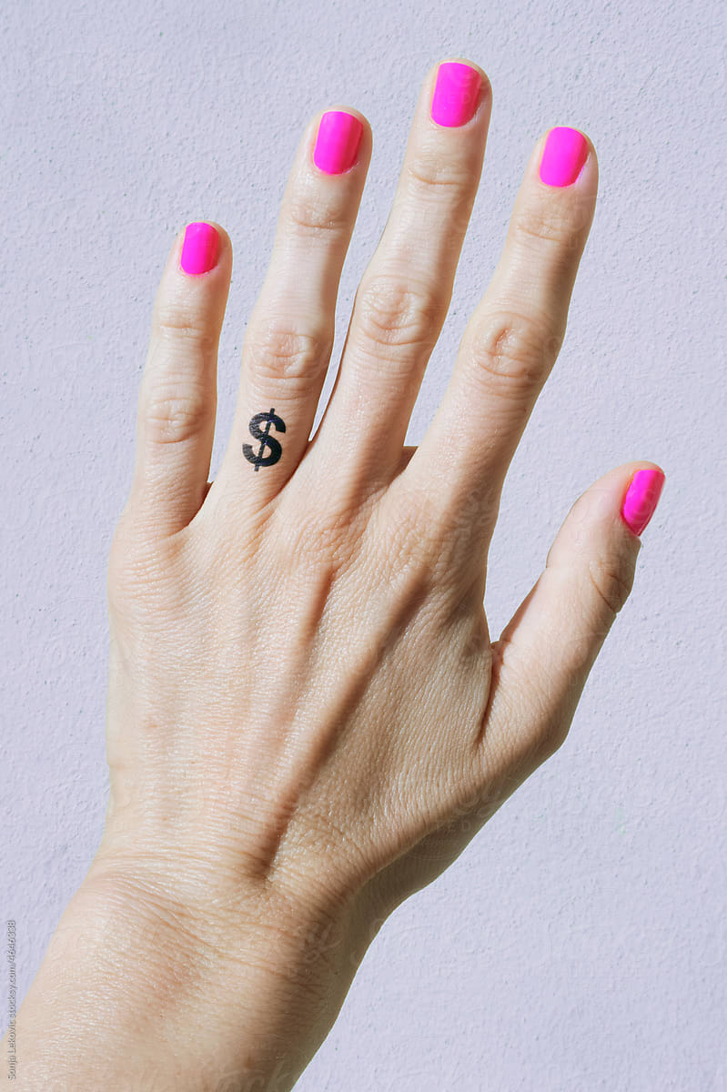 hand with pink nails and a $ tattoo closeup