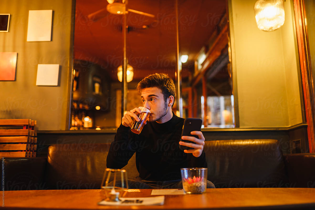 Man with smartphone drinking in bar
