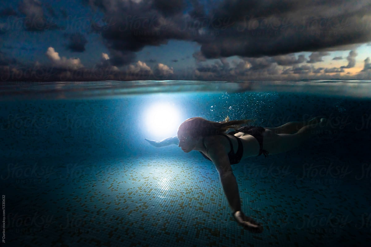 Woman Swimming at Tropical Infinity Pool at Dusk