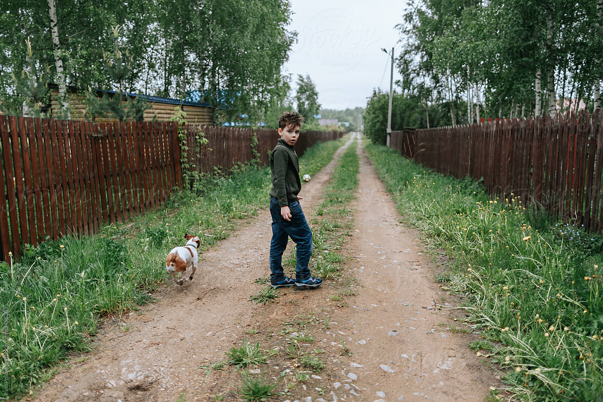Young boy with a ball and a dog in the village