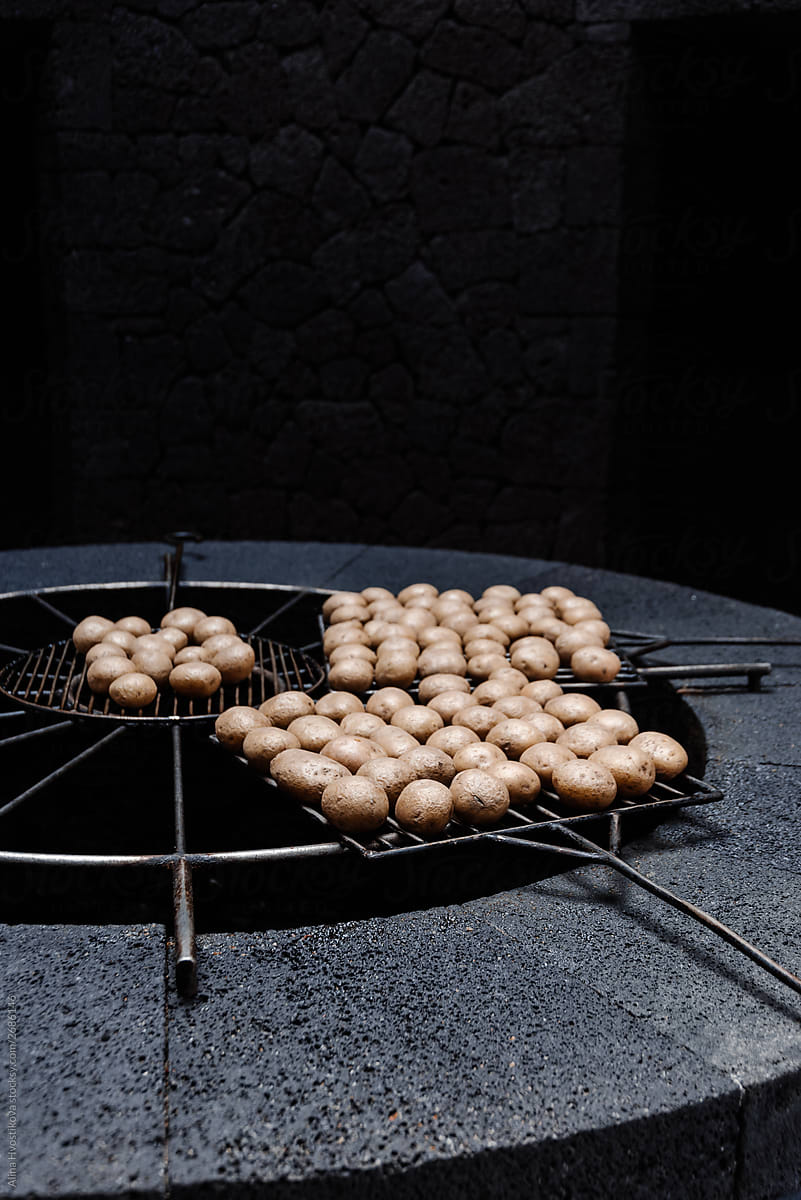 Fry potatoes on grilled grid in darkness cooking.