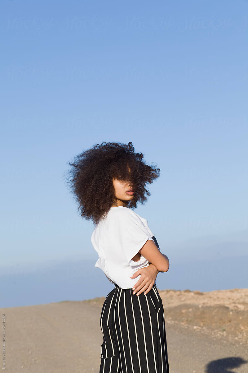 young black woman with curly hair in barren landscape