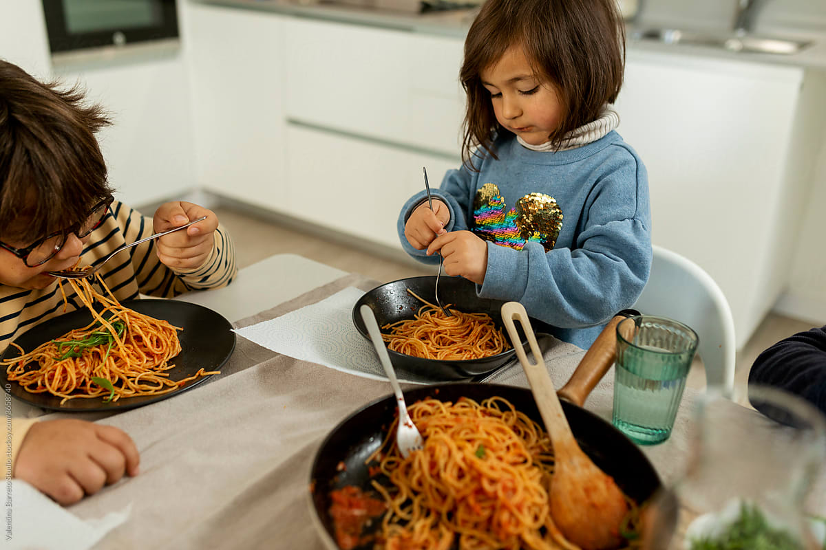 little girl eating pasta at home