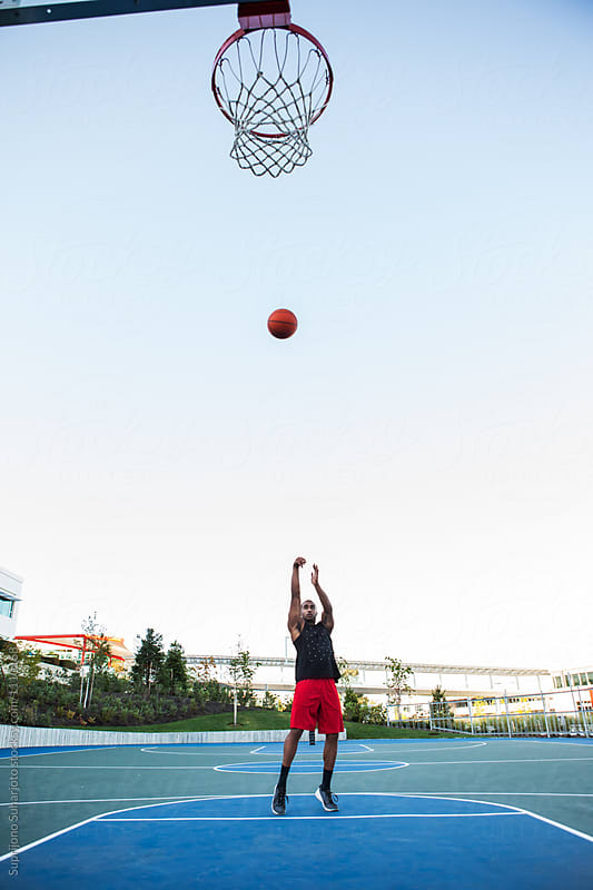 African American man shooting a basketball on an outdoor court