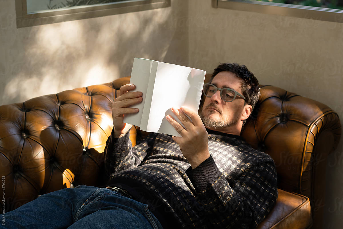 mature man reading a book on sofa