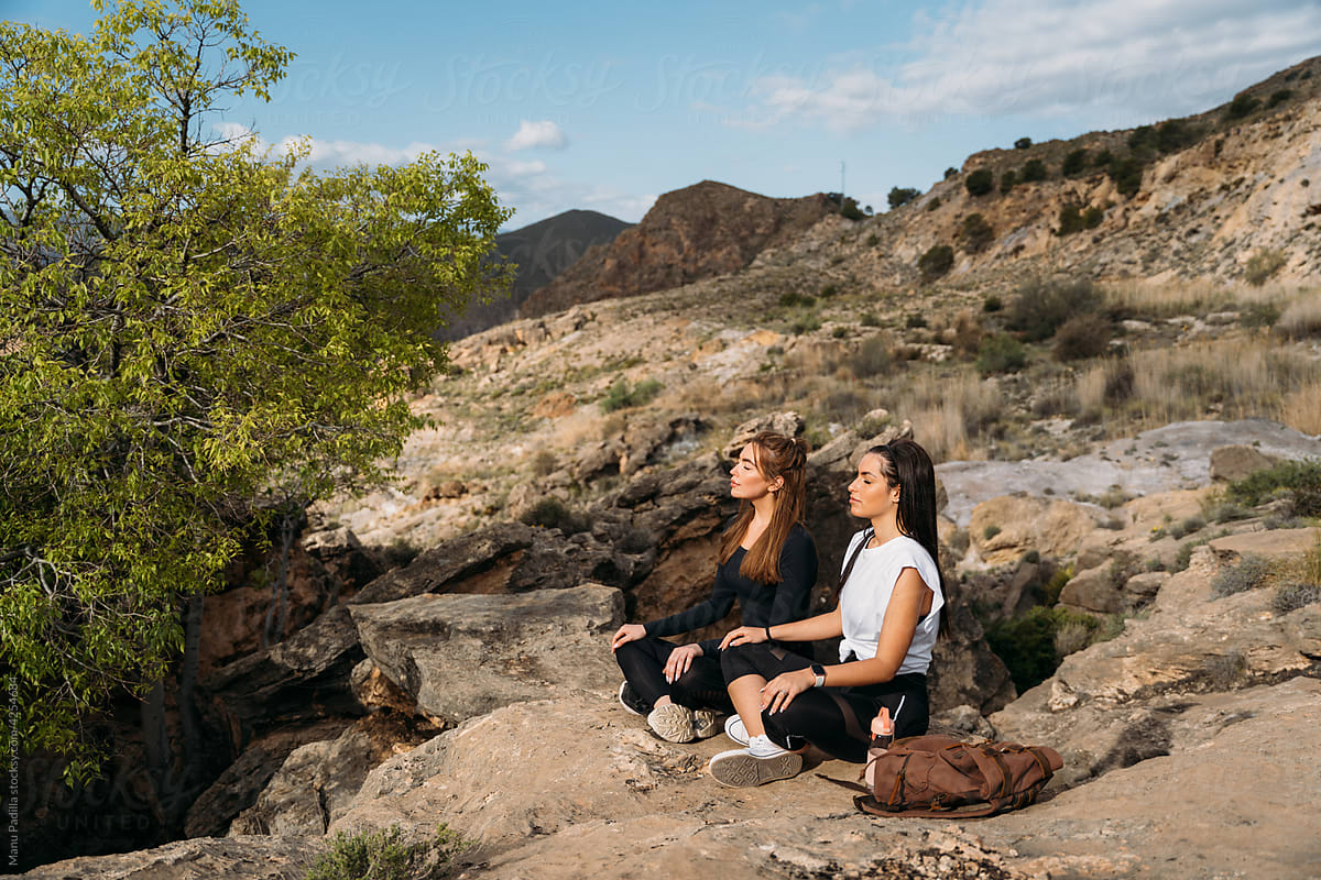 Young women meditating near mountain lake