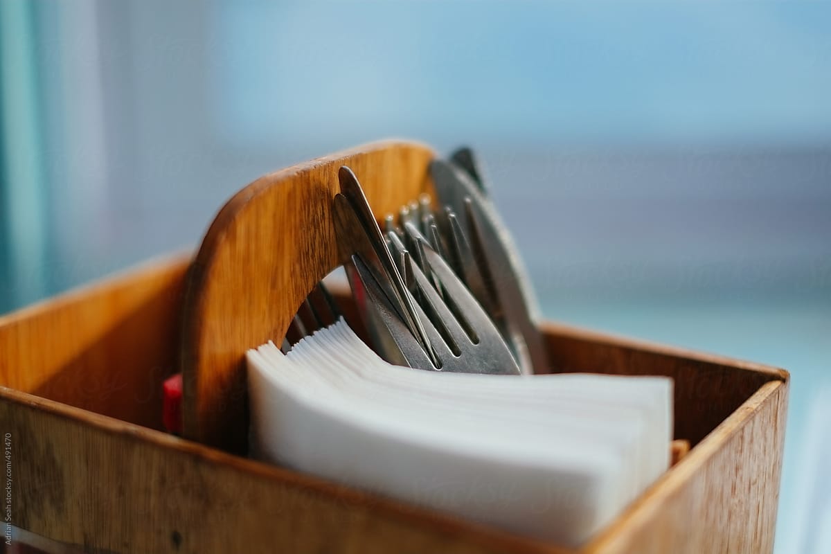 Closeup of cutlery and napkins in a wooden container