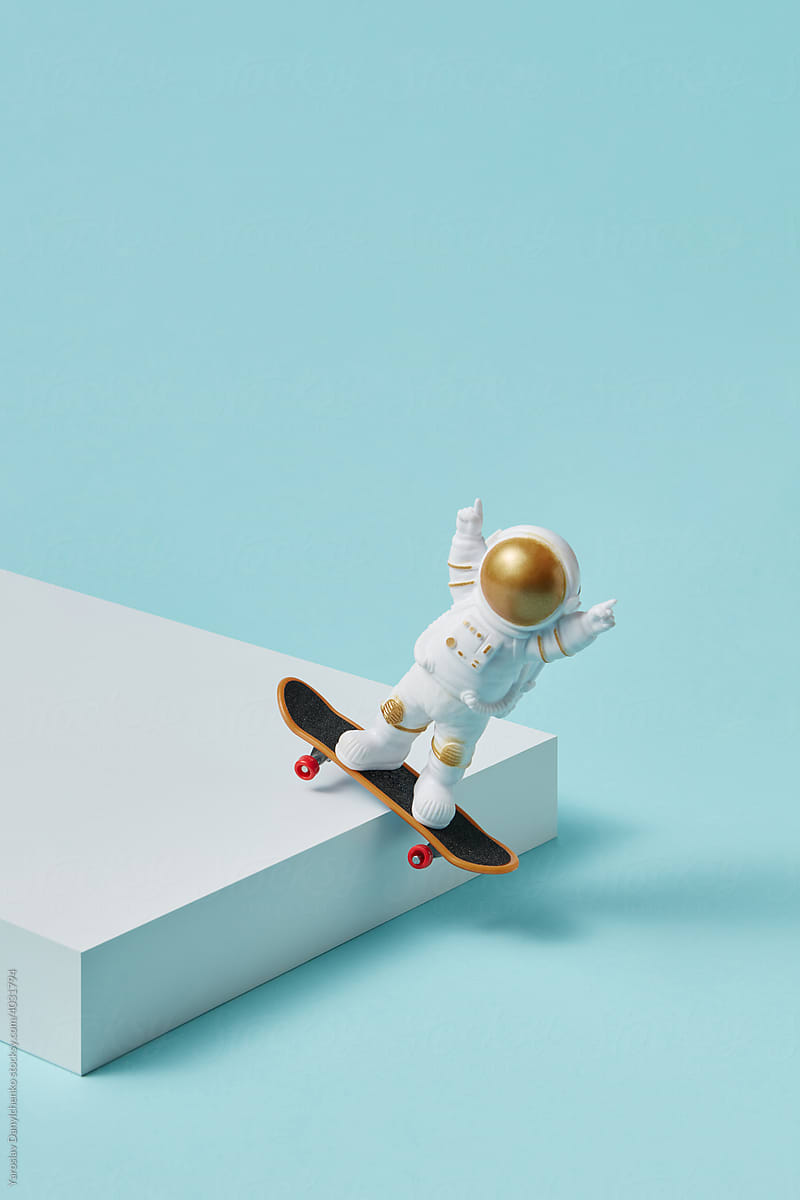 Astronaut with skateboard balancing on box