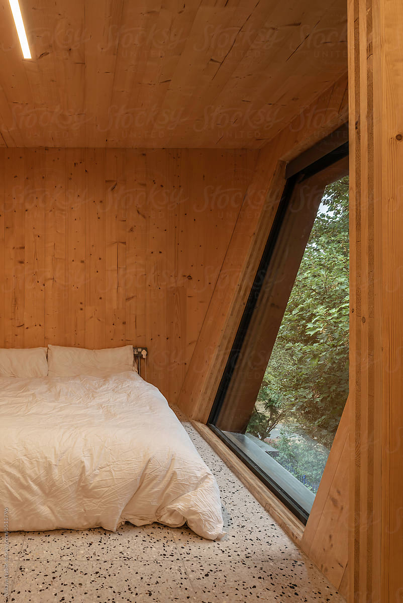 Cozy Bedroom interior lined with timber and a big geometric window